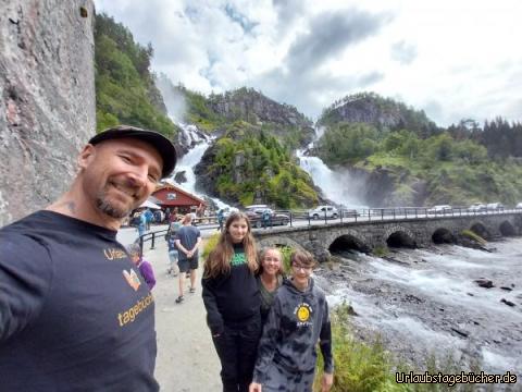 wir am Wasserfall: die Gischt des Doppelkaskadenwasserfalls Låtefoss spritzt bis auf die Straße 