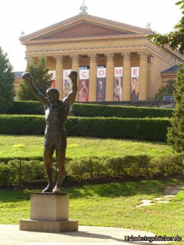 Rocky Statue: aufgrund der Popularität, die das Philadelphia Museum of Art (im Hintergrund)
durch Szenen aus dem Film Rocky (zusätzlich) erlangt hat,
wo Rocky (gespielt von Sylvester Stallone) vor dem Museum jubelte,
wurde direkt vor dem Museum eine Rocky Statue aufgestellt