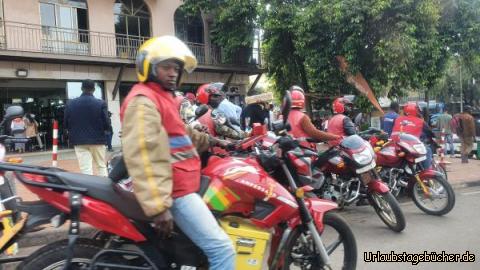 Verkehr in Kigali: Motorradtaxis, hier eine vielgenutzte Dienstleistung. Ein Auto können sich nur die "oberen 10 000" leisten. Alle anderen fahren die relativ billigen Motorrad-Taxis oder auf dem Land die Fahrradtaxis. Busse gibt es wenige, sie fahren vor allem auf den Hauptstraßen über Land.